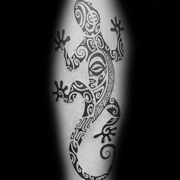 Tribal gecko tattoo with bold black ink, featuring spirals, lines, and symbolic Polynesian patterns across the body and tail.
