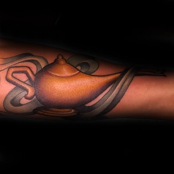 A tattoo of a genie lamp with swirling smoke on an arm