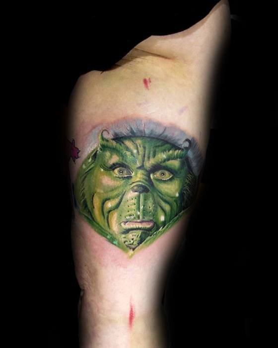 Vividly detailed Grinch face with a mischievous expression, capturing his green features and facial wrinkles, in a colorful and dynamic tattoo design.