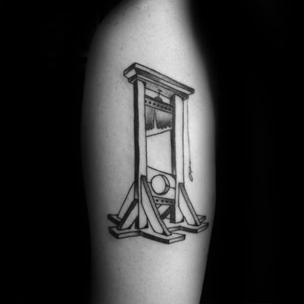 Clean black and grey guillotine tattoo with simple linework, subtle shading, and a classic design showing the blade and headrest.