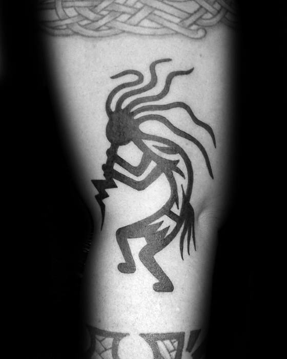 Bold black Kokopelli tattoo with striking lines and geometric patterns, featuring a dynamic flute-playing pose and lightning bolts.