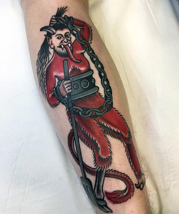 Traditional Krampus tattoo on leg featuring a red devil-like figure holding a pitchfork and chain, with a mischievous grin and hairy limbs.
