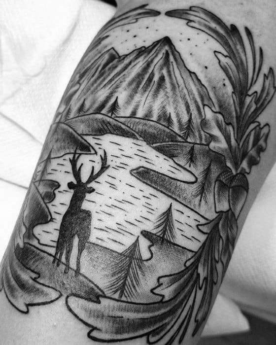 Blackwork tattoo of a deer standing by a lake, with mountain peaks, trees, and ornamental framing in a bold traditional style.