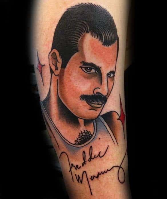 Traditional-style tattoo of Freddie Mercury with bold outlines, red star accents, and his signature inked below the portrait.