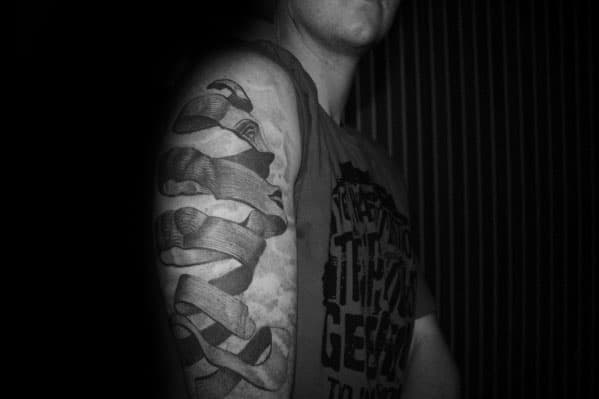 Upper arm tattoo of a twisted ribbon forming the word “Faith” in an MC Escher-inspired 3D woodcut illusion style.