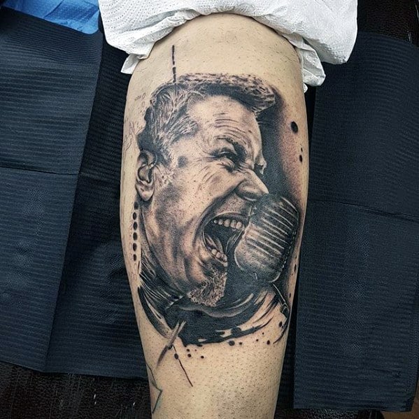 Realistic black and grey tattoo of James Hetfield screaming into a retro microphone, accented with abstract sketch lines and ink splatters.