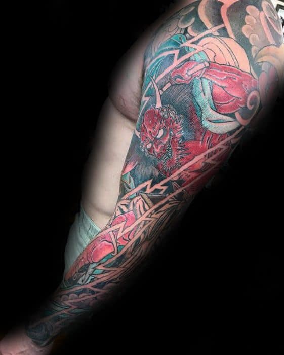 Raijin full sleeve tattoo with red thunder god, white lightning bolts, and swirling wind motifs in bold Japanese traditional style.