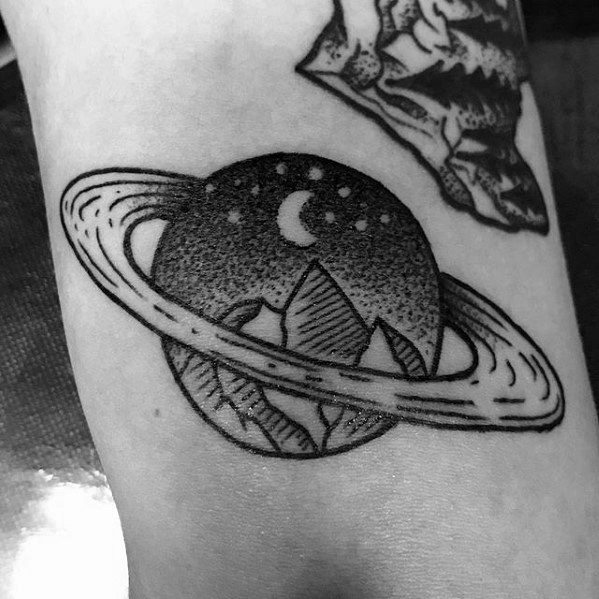 Black line Saturn tattoo design for men with mountain peaks, moon, and stars inside the planet, blending nature and space themes.