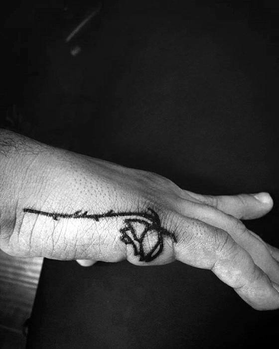 Side hand tattoo for men showing a black rose with a long stem wrapping from the thumb across the outer edge of the hand.