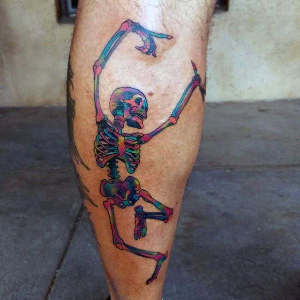 Colorful dancing skeleton tattoo on the calf in Grateful Dead style, with vibrant blue, pink, and green shading.