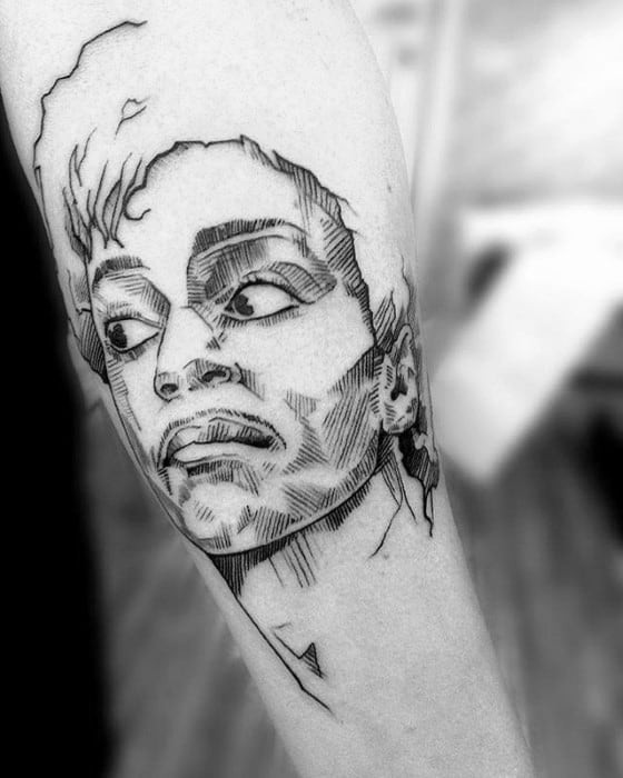 A tattoo of a stylized face resembling Prince in black ink on a person's arm