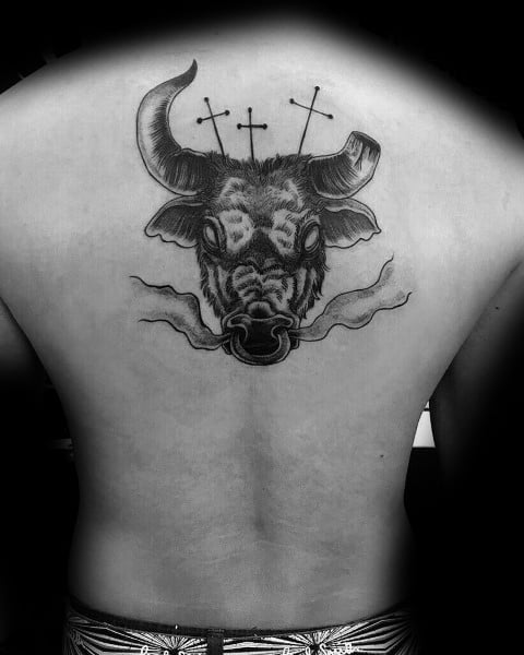 Bold black and grey bull head tattoo on upper back with smoke details and three crosses above, blending symbolism and strength.