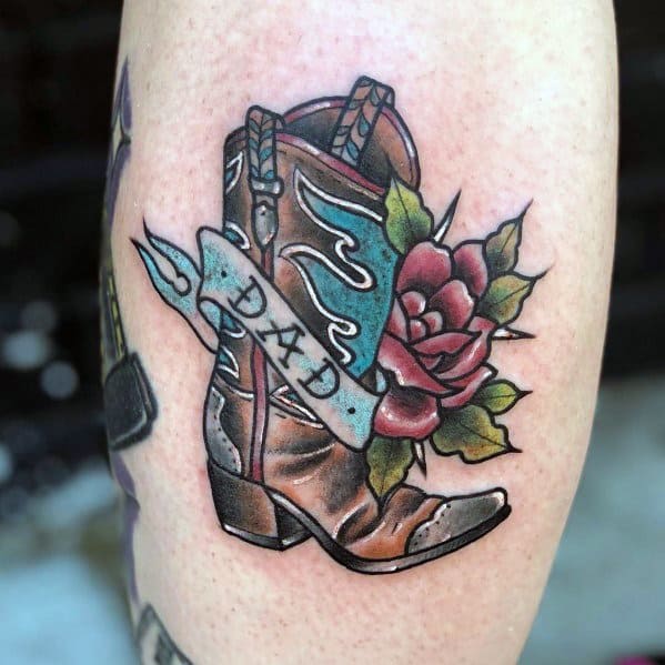 Tattoo of a cowboy boot with a "Dad" banner and a rose, symbolizing love, remembrance, and Western heritage in a bold, colorful design.