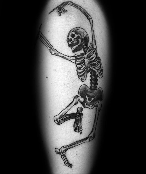 Dancing skeleton tattoo with bold black shading, raised arms, and a playful pose, creating a lively and expressive design on the forearm.