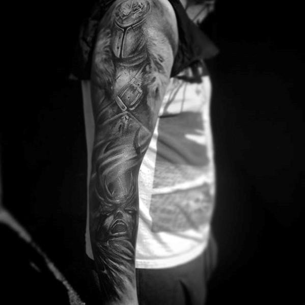 Dark Souls full-sleeve tattoo for men with detailed knight armor, haunting faces, and intense black and grey shading.