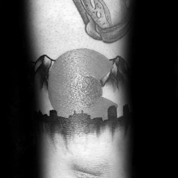 Black and grey Denver skyline tattoo with mountain peaks and a large textured Colorado “C” symbol in the background.