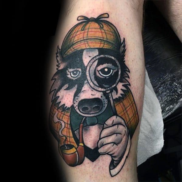 Tattoo of a dog dressed as Sherlock Holmes, complete with detective hat, pipe, and magnifying glass