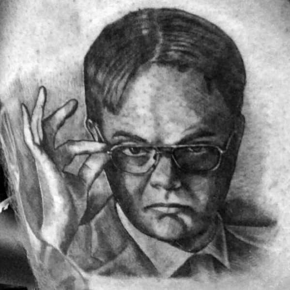Black and grey tattoo of Dwight Schrute adjusting his glasses with a serious expression, featuring detailed shading and realistic portrait style.