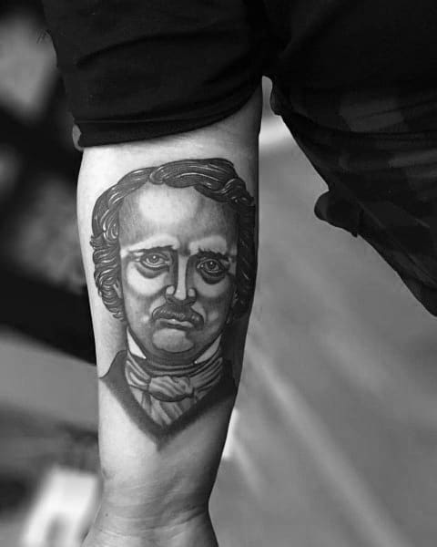 Black and grey forearm tattoo of Edgar Allan Poe with bold outlines, stylized shading, and a somber, intense expression.