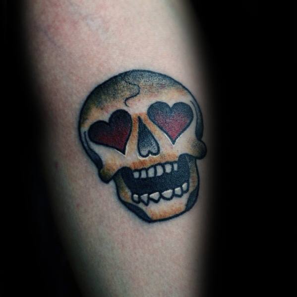 Skull tattoo with heart-shaped eye sockets looks like an edgy emoji on the skin