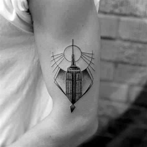Geometric Empire State Building tattoo with a sunburst design, delicately inked in black on a man's upper arm.