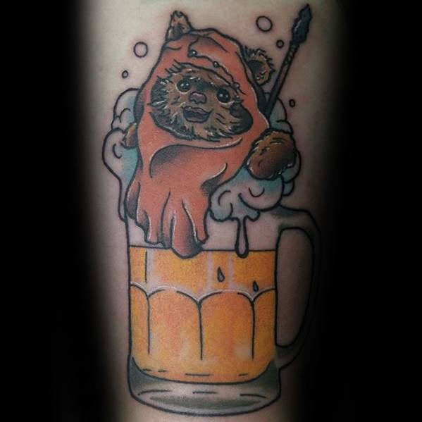 Playful Ewok tattoo popping out of a frothy beer mug with a spear, blending Star Wars humor with bold, cartoon-style art.