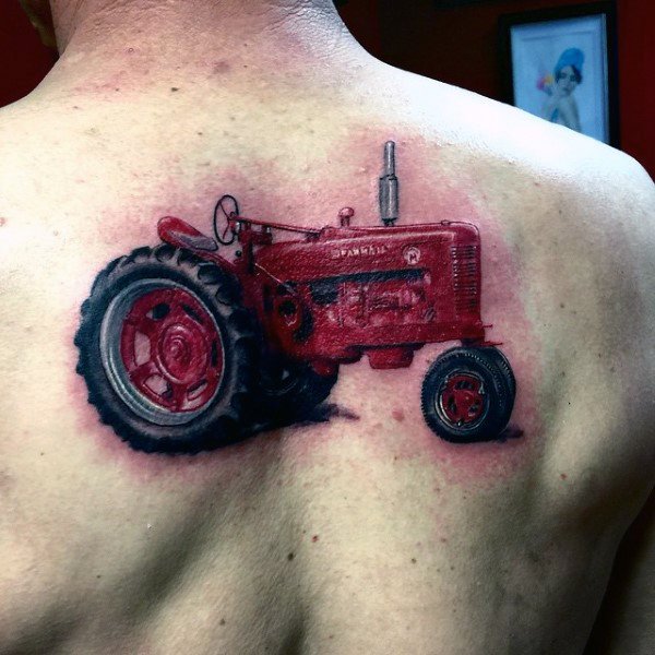 Bold red tattoo of a vintage Farmall tractor on the upper back, detailed with shadowing for a realistic three-dimensional effect.