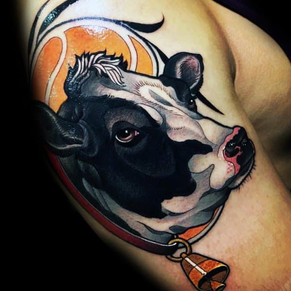 Vibrant upper arm tattoo of a black and white cow with a bell collar, set against an orange and black abstract background.