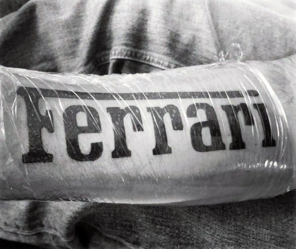 Bold tattoo of the Ferrari logo text prominently inked on man's forearm, highlighting pride in the iconic automotive brand.