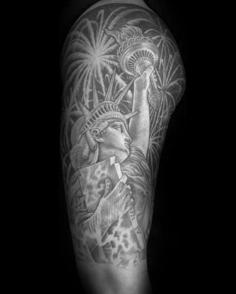 Black and grey tattoo of the Statue of Liberty with detailed shading, surrounded by fireworks, creating a bold and patriotic design.