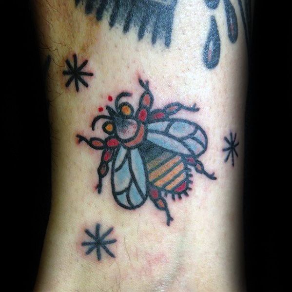 Traditional-style fly tattoo with bold black outlines, orange and red accents, and decorative starbursts for a fun, retro vibe.