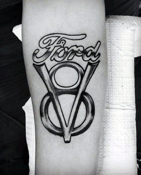 Bold black and grey Ford V8 logo tattoo on forearm, featuring clean lettering, strong shading, and a classic vintage automotive design.
