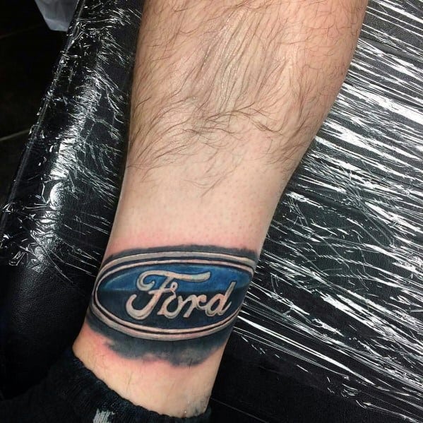 Realistic Ford logo tattoo on wrist, featuring a bold blue emblem with intricate shading and a 3D effect for a striking design.