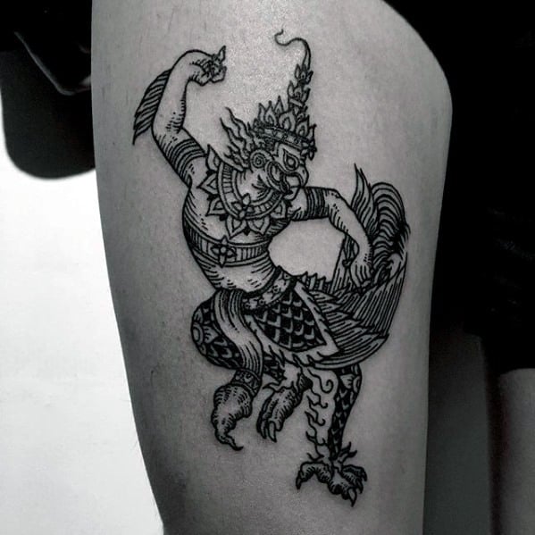 Garuda tattoo on the thigh in traditional line art style, showing a dynamic pose with raised arm, ornate headpiece, and bird-like legs.