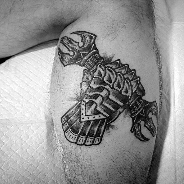 Black and grey tattoo of a medieval armored gauntlet gripping a double-headed axe, detailed with bold lines and intricate shading.