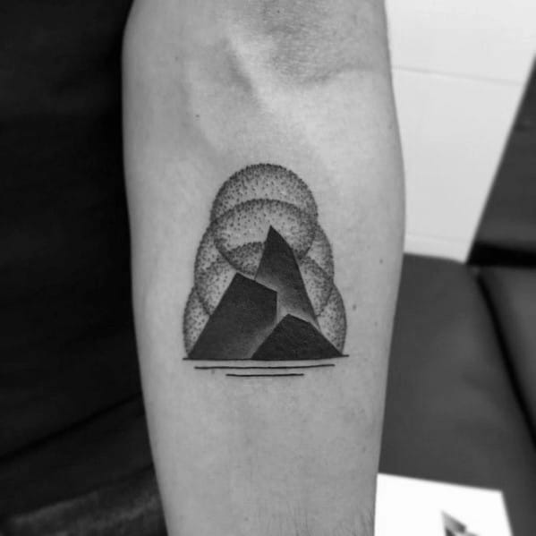 Bold black mountain tattoo with layered dotwork clouds in the background and minimalist horizontal lines at the base.
