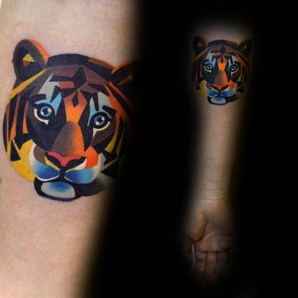Vibrant geometric tiger tattoo on forearm with bold color blocks in orange, blue, and yellow, creating a striking modern look.