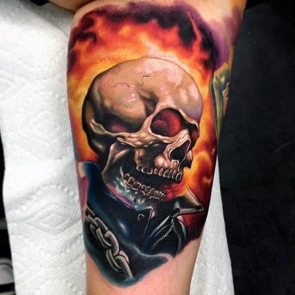 Realistic Ghost Rider tattoo with a cracked flaming skull, fiery background, leather jacket, and bold chain in vibrant colors.
