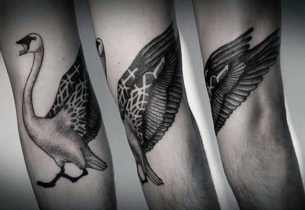 Black and gray tattoo of a goose with geometric patterns on its wings, shown in both walking and flying poses, inked with bold shading and intricate details.