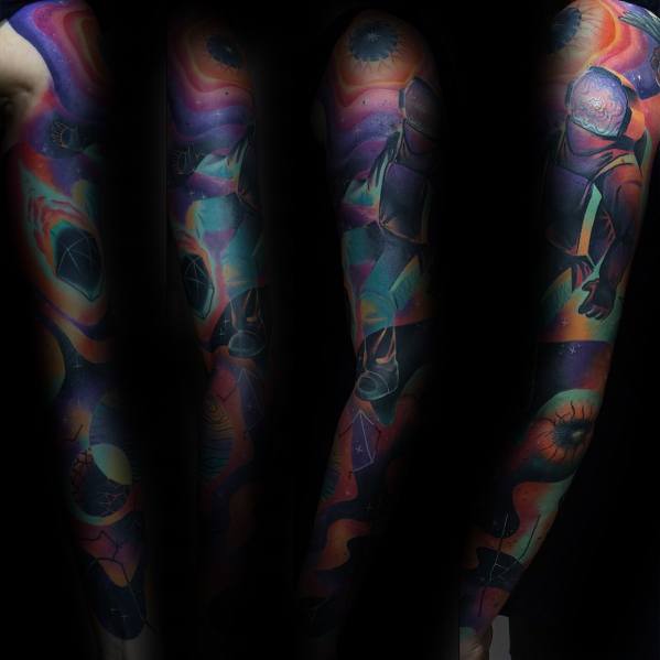 Full sleeve tattoo with a cosmic theme, featuring an astronaut, planets, and swirling galaxies in vibrant purple, blue, orange, and green gradients.