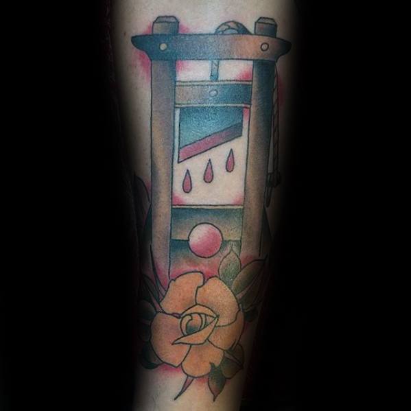 Colorful guillotine tattoo with soft shading, three red blood drops, a yellow rose at the base, and a pastel-toned background.