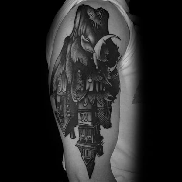 Upper arm tattoo of an upside-down haunted house transforming into a cloaked ghostly figure with a crescent moon and eerie shading.