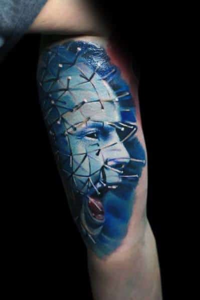 Realistic *Hellraiser* tattoo of Pinhead with vivid blue tones, intricate pin details, and a screaming expression for a haunting and intense design.