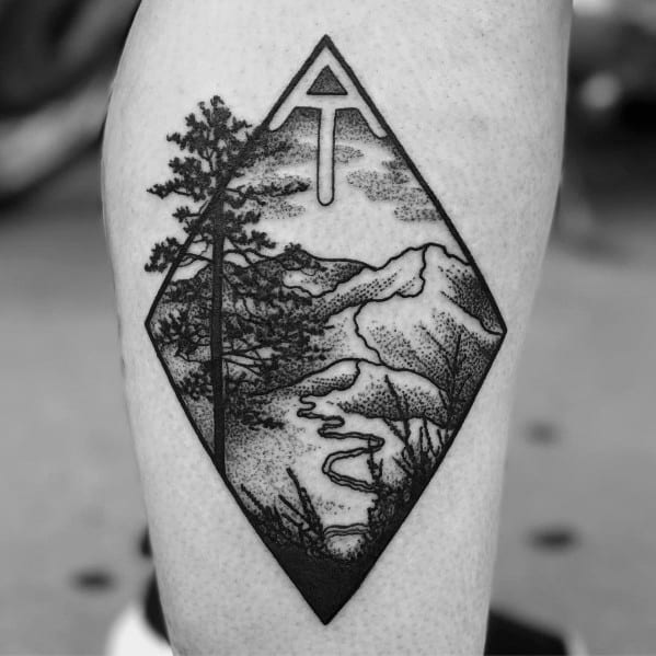 A black and gray tattoo featuring a tall tree on one leg and a small hiker silhouette on the other, symbolizing a love for the outdoors.