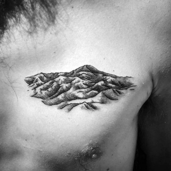 Detailed black and white chest tattoo of a rugged mountain range, symbolizing strength, resilience, and a love for nature.