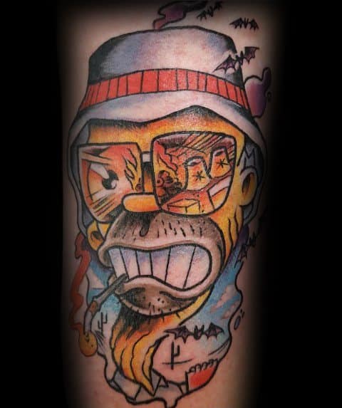 Bold and colorful Hunter S. Thompson-inspired tattoo featuring a cartoonish, exaggerated portrait with aviator glasses reflecting a desert scene, bats, and a cigarette.