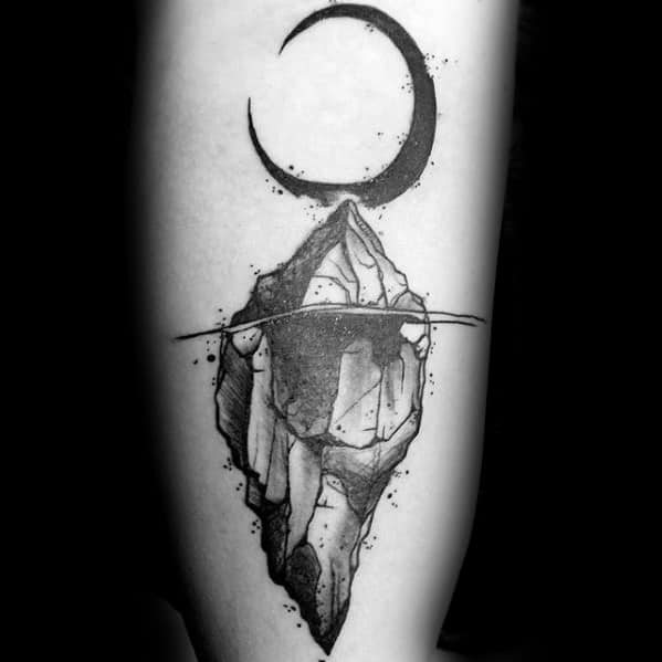 Black and grey iceberg tattoo with textured shading, a crescent moon above, and splatter details surrounding the floating ice.
