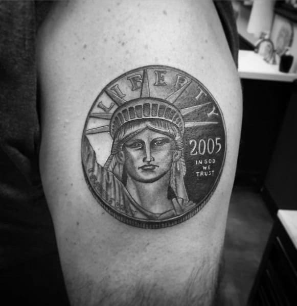 Realistic tattoo of a 2005 Liberty coin featuring the Statue of Liberty, detailed shading, and bold lettering on the upper arm.