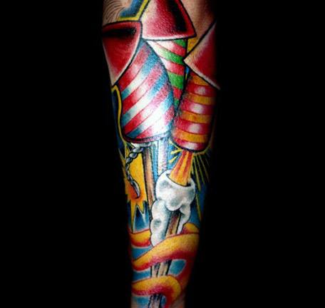 Bold and colorful tattoo featuring large rocket fireworks launching with smoke and sparks, designed in a vibrant traditional style.