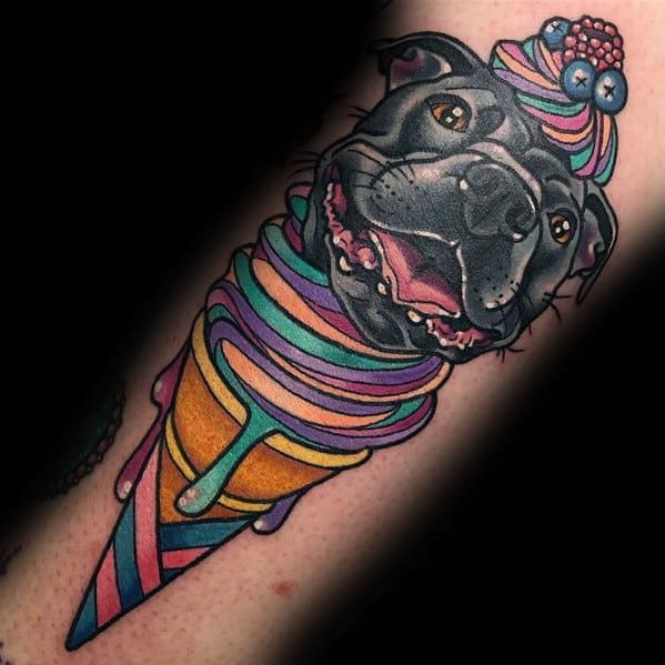 Colorful tattoo of a happy black dog with its head merging into a vibrant melting ice cream cone, topped with berries and whipped cream for a playful design.